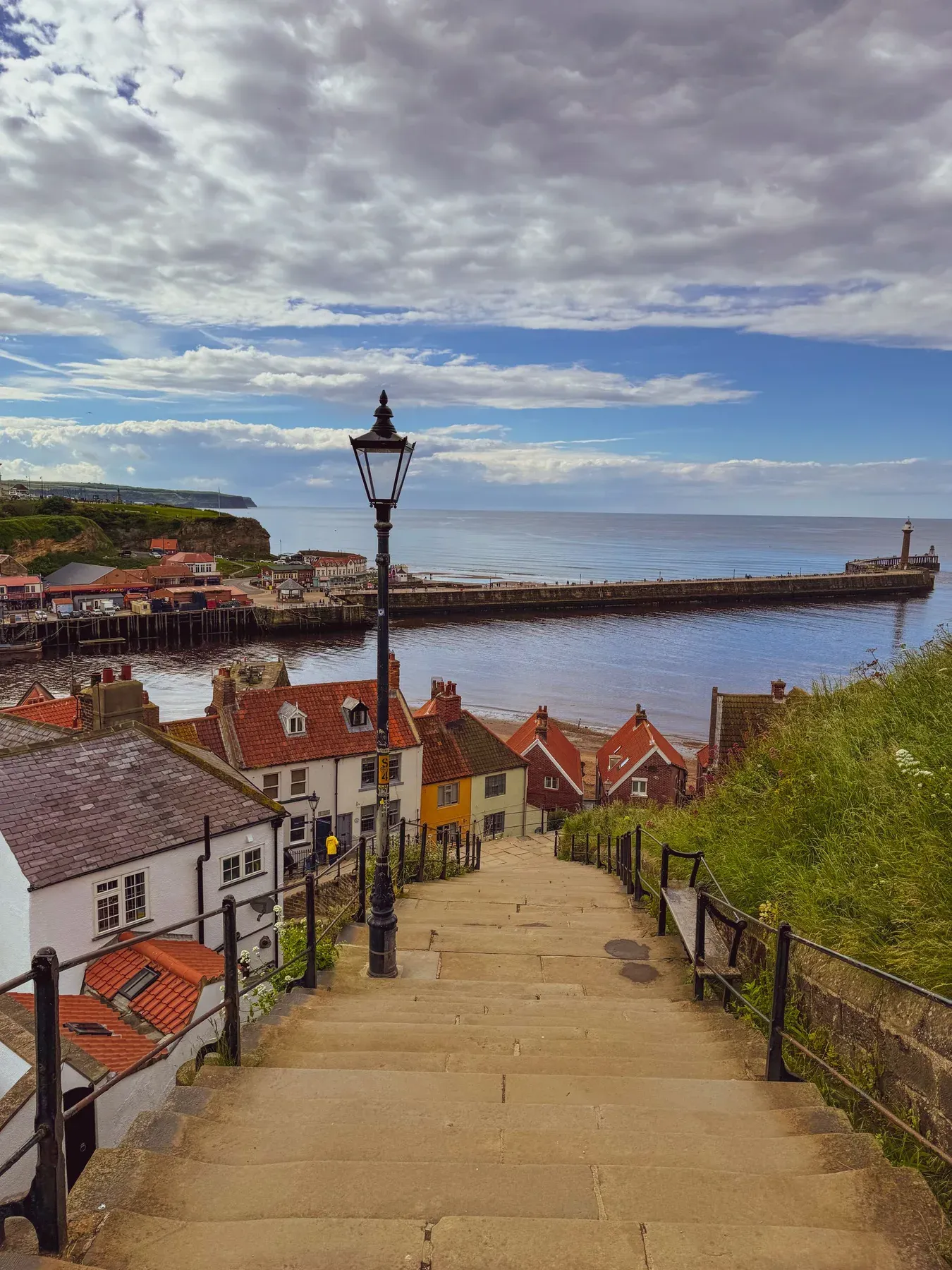 Looking down the 199 Steps over the rooftops to Whitby harbour and the West Pier lighthouse