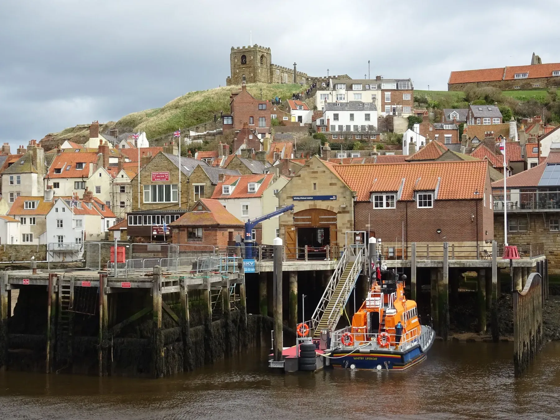 Whitby harbour with the lifeboat station, red pantile roofs and St Mary's Church on the headland above